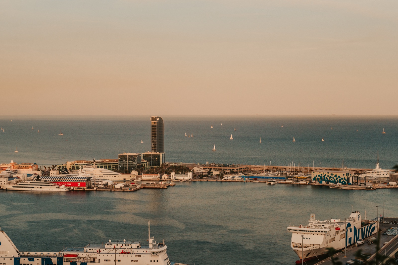 The port and the open sea, with ferries below and sailing boats on the horizon